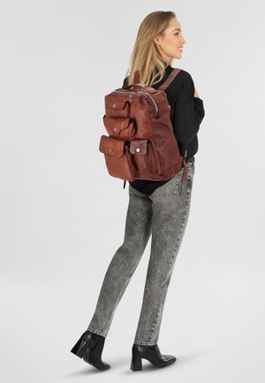 Sac à dos en cuir marron avec plusieurs poches avant, des sangles réglables et une fermeture éclair. Texture lisse et design durable.