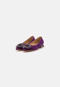 Ballerines en daim violet avec des pointes effilées, ornées d'un nœud bijou et dotées d'un talon bloc accentué. Doublure intérieure lisse.