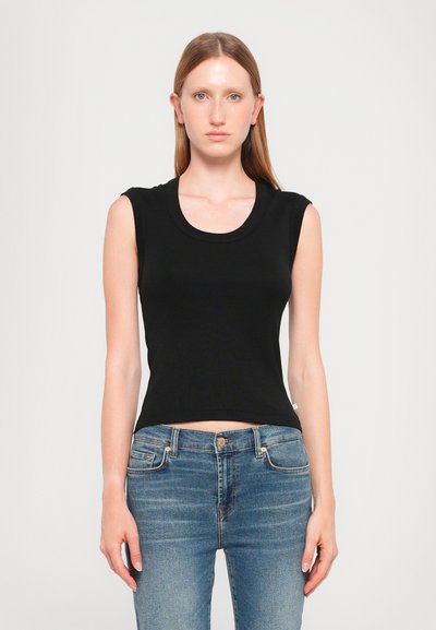 Μαύρο αμάνικο crop top με στρογγυλή λαιμόκοψη, φτιαγμένο από μαλακό ύφασμα. Απλός σχεδιασμός, συνδυασμένο με ανοιχτό μπλε, στενό τζιν.