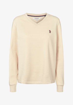 Bežs v veida sporta krekls ar garām piedurknēm, izgatavots no mīksta auduma. Izšūts logo uz krūškurvja. Iespējas ar ribotiem manšetēm un apaļu kakla izgriezumu.