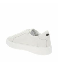Zapatilla de cuero blanca con punta redonda y suela de goma plana. Presenta cordones en tono y un logotipo negro en contraste en el talón. Textura suave.