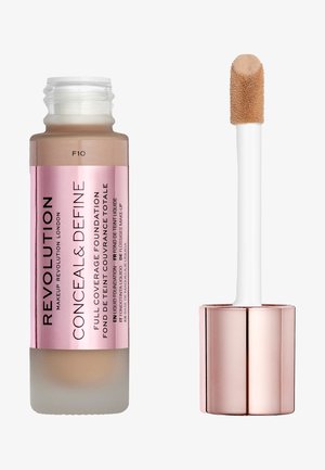 Base de maquillaje de cobertura total en un frasco de vidrio esmerilado con una etiqueta rosa, que incluye un aplicador blanco con una punta difusa. Tono de color F10.