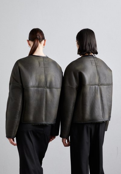 Dunkelgrüne Lederjacke mit kastenförmigem Design und weiten Ärmeln, ausgestattet mit genähten Panels und einem rohen Saum auf der Rückseite.