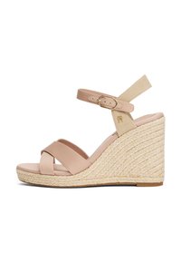 Wedge sandal with a beige leather upper, crisscross straps over the toes, and a woven jute heel. Features a buckle closure and soft footbed.