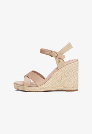 Sandaš s klinastom petom s bež kožnim gornjom, prepletenim trakama preko prstiju i tkanom jutenom potpeticom. Ima kopčanje sa metalnom kopčom i mekanu unutrašnjost.