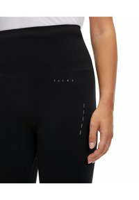 Leggings neri a vita alta con una fascia testurizzata e un sottile logo FALKE. Presentano una tasca laterale con un dettaglio decorativo di cucitura a tratteggio.