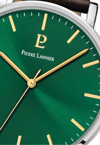 Zielony cyferblat z złotymi znacznikami godzin i wskazówkami. Logo "Pierre Lannier" w kolorze białym. Srebrna metalowa koperta i brązowy skórzany pasek.