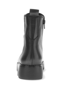 Botín de cuero negro hasta el tobillo con suela gruesa y tirador trasero, mostrando vista trasera y cremallera lateral sobre fondo blanco.
