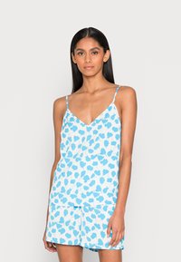 Conjunto de camisola e calções com padrão floral azul e branco, feito de tecido leve. Apresenta alças finas e um design de corte solto.