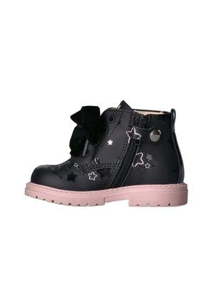 Stivaletto alla caviglia in pelle verniciata nera con fori a forma di stella, suola rosa, zip laterale e grande fiocco nero frontale. Design chunky, superficie texturizzata.
