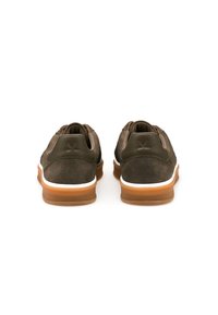 Chaussures en daim vert foncé avec un dessus texturé, une semelle intermédiaire blanche et une semelle extérieure en caoutchouc marron. La vue arrière met en valeur le col rembourré et les détails de couture.