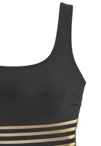 Haut de maillot de bain noir avec de larges bretelles, présentant des accents horizontaux en rayures métalliques dorées à la taille. Tissu lisse et extensible.