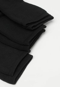 Schwarze, gerippte Baumwollsocken, ordentlich gefaltet, die eine weiche Textur und glatte Oberfläche zeigen, mit verstärkten Bündchen für zusätzliche Haltbarkeit.