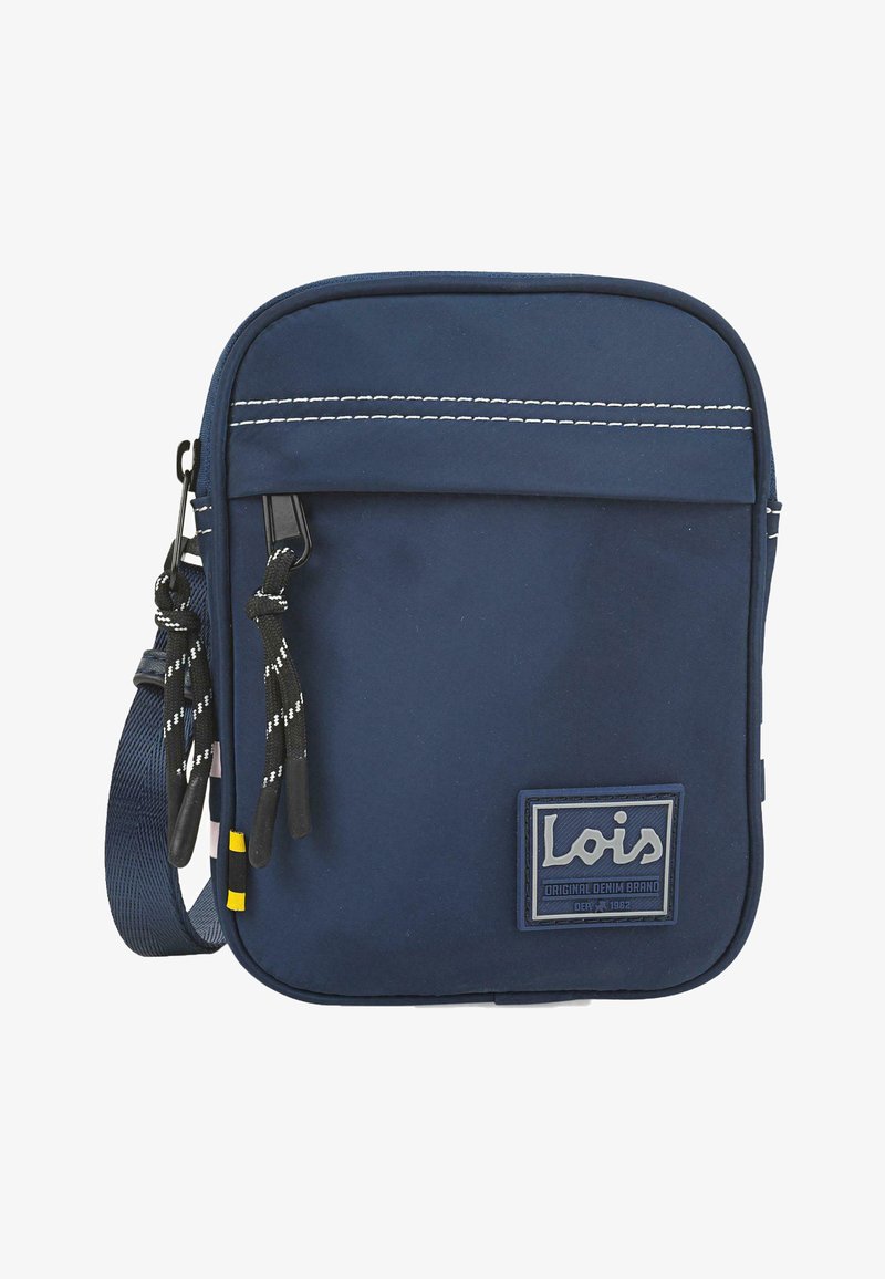 Bolsa de tela suave de color azul marino con costuras en blanco, cierre de cremallera, correa ajustable y un parche de marca. Presenta dos tiradores de cordón negro.