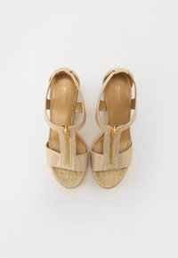 Sandales beiges avec un dessus en tissu texturé, dotées de deux sangles zippées, d'une semelle intérieure douce et d'une finition zippée en ton doré.