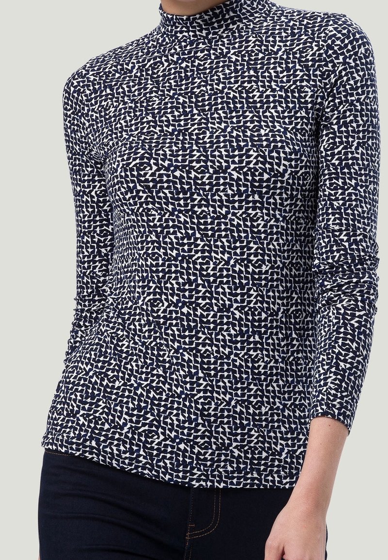 T-shirt à manches longues avec col roulé dans un motif géométrique bleu marine et blanc, fabriqué en tissu stretch lisse. Il présente une coupe ajustée et un col haut.