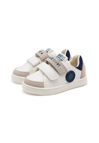 Sneaker bianche con accenti beige, cinturini in velcro, materiali in tessuto e suede, patch con logo blu e suola in gomma testurizzata.
