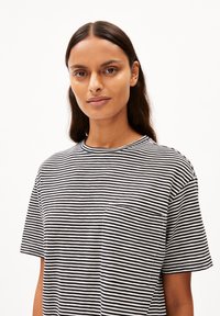Gestreiftes T-Shirt in Schwarz und Weiß, mit rundem Ausschnitt, kurzen Ärmeln und einer linken Brusttasche. Weiches Baumwollmaterial.