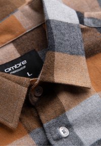 Brązowa i szara koszula flanelowa w kratę z kołnierzykiem, z dwoma guzikami i metką z napisem "Ombre menswear" w rozmiarze L.