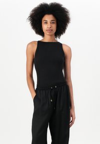 Top preto canelado com um design justo e alças largas, combinado com calças pretas com cordão, com uma textura suave e um hardware discreto.