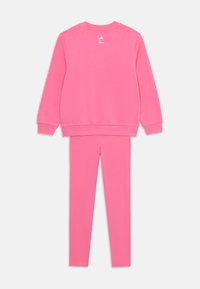 Ružový bavlnený set so Sweatshirtom a legínami. Sweatshirt má okrúhly výstrih a rebrované manžety, zatiaľ čo legíny majú hladkú textúru a úzky strih.