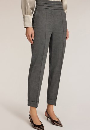 Graue maßgeschneiderte Hose mit strukturiertem Muster, hoher Taille, Falten und umgeschlagenen Säumen, kombiniert mit glänzenden spitzen Absatzschuhen.