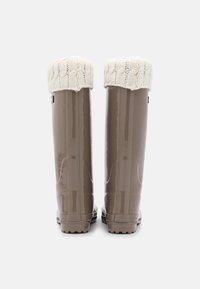 Bottes de pluie en caoutchouc imperméables marron avec un revers tricoté texturé en blanc cassé. Surface lisse et semelles nervurées pour une meilleure adhérence.