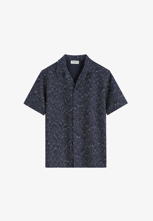 Chemise bleu marine à manches courtes avec un petit motif tacheté blanc et col camp, étiquetée "FRILIVIN" à l’intérieur du col.