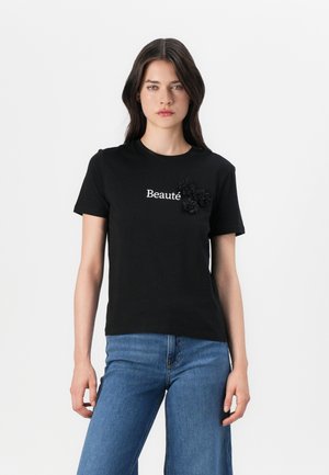 T-shirt en coton noir avec impression blanche "Beauté" et appliqués floraux en relief noirs sur la gauche. Design classique à col rond.