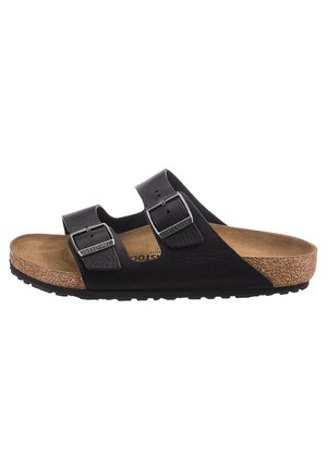 Black two-strap sandal with buckle accents, cork footbed, and textured rubber sole. Flat design, open toe, and contoured support.