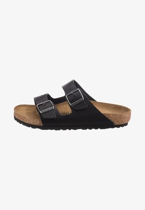 Black two-strap sandal with buckle accents, cork footbed, and textured rubber sole. Flat design, open toe, and contoured support.