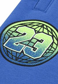 Blauwe stof met een cirkelvormige graphic waarin het nummer "23" staat in levendig groen en blauw, met een textuurdetail, omringd door een gloob ontwerp.