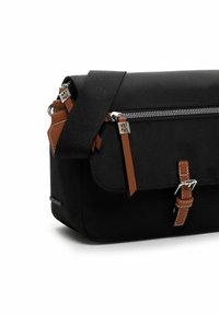 Schwarze rechteckige Umhängetasche mit braunem Leder-Reißverschlusszug und Schnallendetails vor weißem Hintergrund.