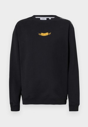 Svart crewneck genser med en liten gul "Carlo Colucci Milano 1978" logo på brystet og logo tekst på høyre skulder.