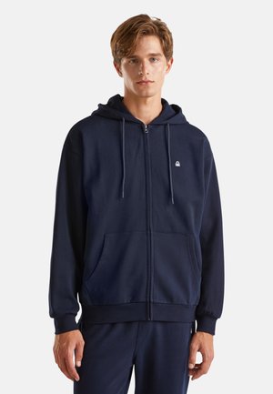 Marineblauwe zip-up hoodie van zachte stof met een voork Pocket, verstelbare trekkoordcapuchon en logo op de borst. Casual pasvorm met ribgebreide manchetten.