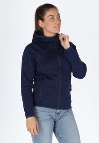Giacca in fleece blu navy con zip frontale, cappuccio sagomato e due tasche laterali. Tessuto testurizzato con un motivo sottile e zip a contrasto.