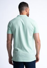 Mintgrön polo skjorta i bomull med korta ärmar, en vanlig passform och en klassisk krage. Enkel textur utan synliga mönster.