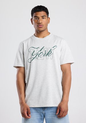 T-shirt gris clair à manches courtes en tissu doux, avec un motif "NEW York" en vert foncé. Coupe décontractée, encolure arrondie.