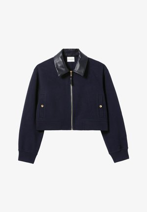 Chaqueta corta azul marino con un cuello de cuero negro, cremallera dorada y dos bolsillos frontales con botones dorados. Tejido suave y puños acanalados.