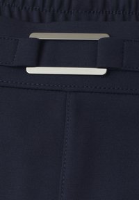 Tissu bleu marine avec une boucle de ceinture rectangulaire argentée et une ceinture élastique avec coutures visibles.