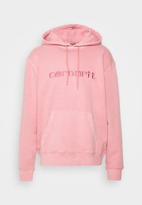 Světl růžová mikina s kapucí na stažení a přední kapsou. Má vyšívané logo "carhartt." v tmavším odstínu růžové. Měkká texturovaná látka.