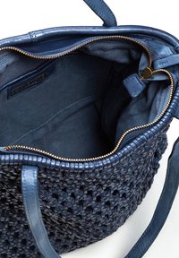 Bolso de mano tejido en color navy con detalles en cuero, cierre de cremallera y forro interior suave. Presenta dos asas y detalles en hardware dorado.