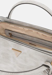 Light gray handbag with a textured exterior, gold hardware, and a triangular logo. Interior features multiple compartments and beige lining.