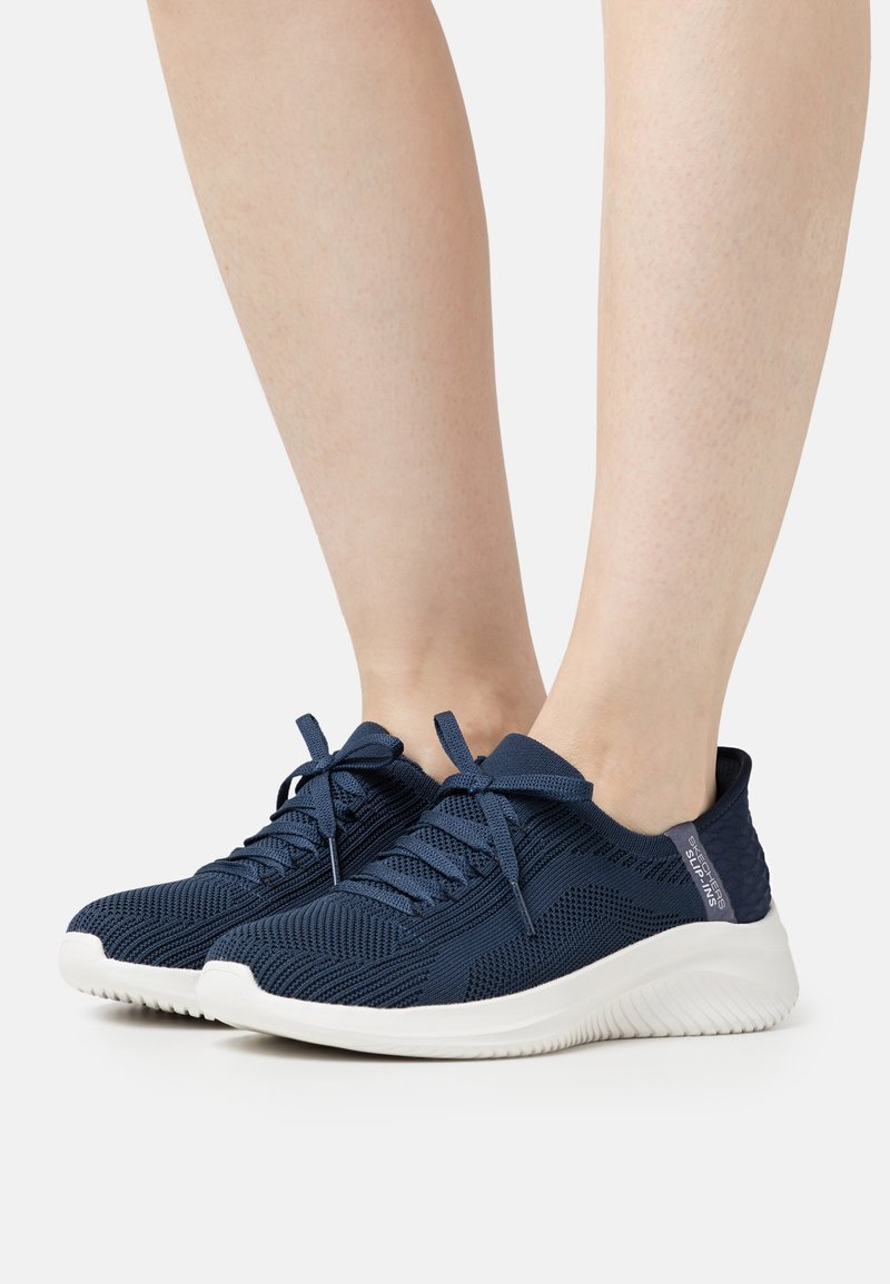 Baskets de sport bleu marine avec dessus en mesh, semelle blanche et lacets. Présentent des accents texturés et un col rembourré pour le confort.