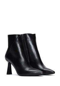 Zwarte leren enkellaarsjes met een spitse neus en een stilettohak. Voorzien van een rits aan de zijkant en een gladde, glanzende textuur.
