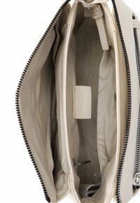 Balta ādas soma ar rāvējslēdzēju. Iekšpusē ir vairākas nodalījumu vietas, teksturēts audums un mazs kabatiņa ar spiedpogu aizdari.