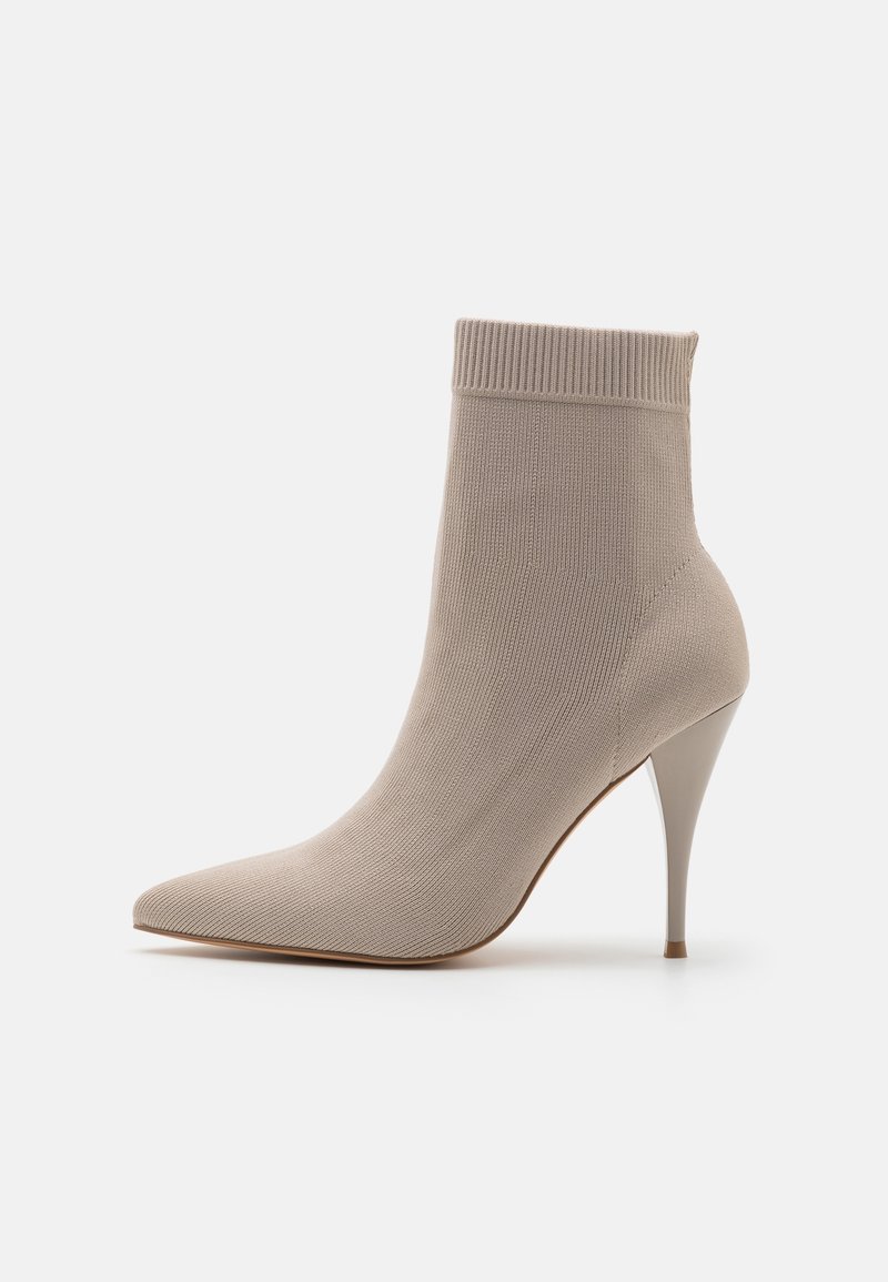 Bottine beige en maille avec un bout pointu, un bord côtelé et un talon stiletto haut. Texture lisse avec une silhouette ajustée.