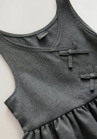Robe sans manches grise avec un décolleté en V, ornée de deux nœuds décoratifs et d'un ourlet volanté. Fabriquée à partir d'un tissu doux et texturé.