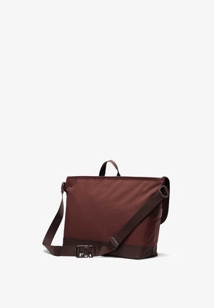 Bruine stoffen schoudertas met een vlakke, rechthoekige vorm, verstelbare band, bovenhandvat en een stevige gesp. Textuur op het oppervlak heeft een matte afwerking.