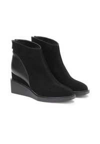 Stivaletti neri in suede con tacco a zeppa. Presentano un elegante dettaglio laterale e una punta chiusa con chiusura a cerniera sul retro.